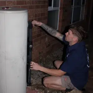 A Emergency plumber in the dark working on a Hot Water Service as part of Emergency Plumbing Services Gold Coast