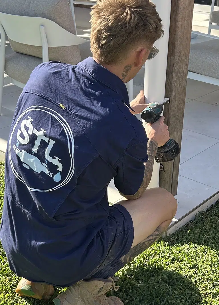 Licenced Plumber Sam Lennox is Attaching a downpipe to an outdoor patio area, Renovation Plumbing on the Gold Coast