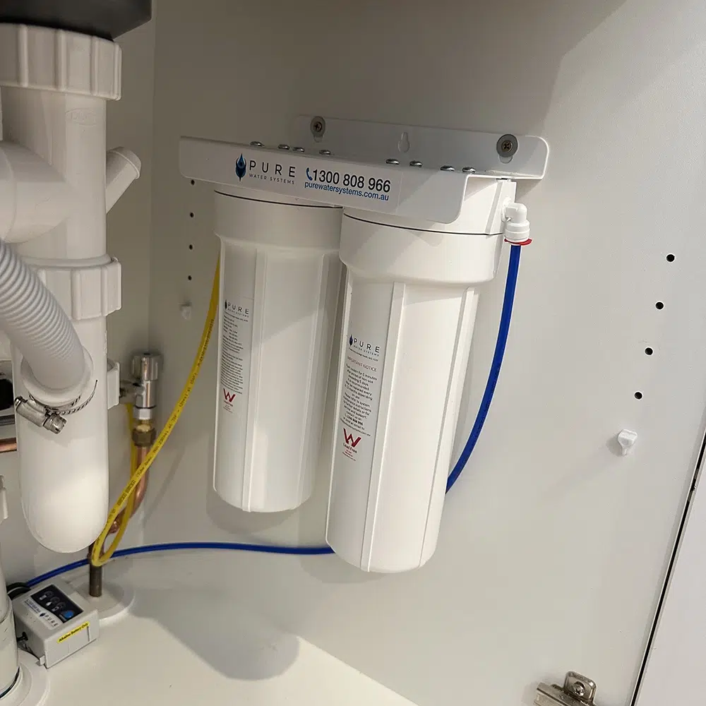 A compact white plastic under sink water filtration unit installed in a Gold Coast home by STL Plumbing