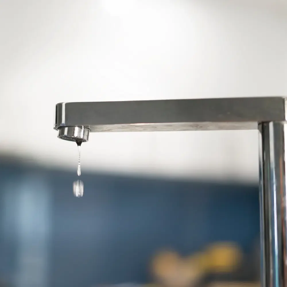 A modern silver kitchen tap leaking. For immediate bookings call STL Plumbing