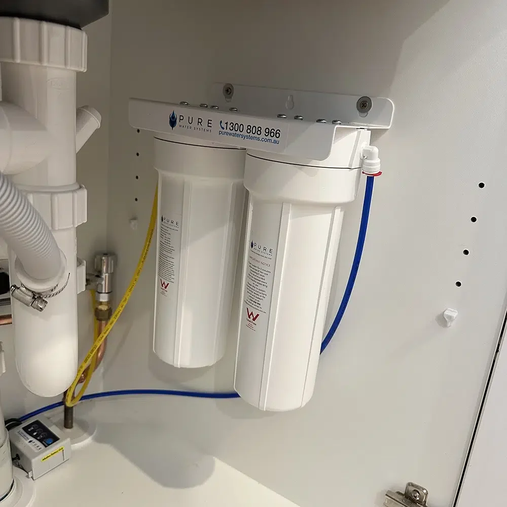 A compact white plastic under sink water filtration unit installed in a Gold Coast home by STL Plumbing